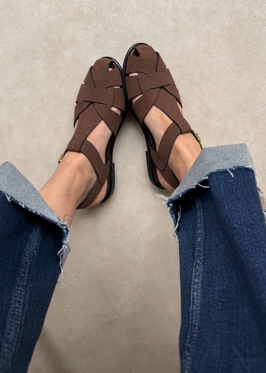 Brown sandals worn with blue jeans on a neutral background